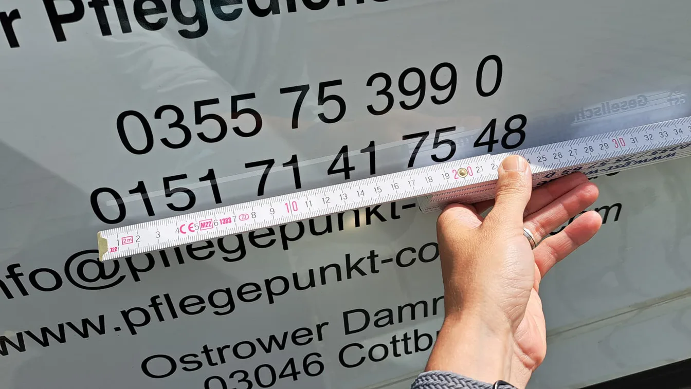 Detailaufnahme bei der präzisen Kontrolle einer Fahrzeugbeschriftung